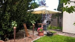 A patio area with a table and chairs under a canopy, surrounded by potted plants and a wooden fence. - Holiday Home Niederehe Romantic Escape (Üxheim)