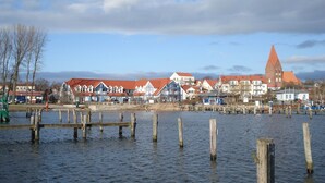 Un pueblo frente al mar con edificios tradicionales y una destacada torre de iglesia.