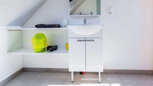 A modern bathroom with a white vanity, a sink, and a mirror. There is a towel rack above the vanity and a shelf below it. - Apartment in Watou Near French Border (Poperinge)