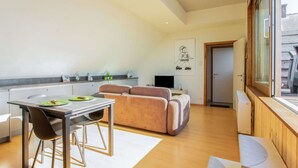 A modern kitchen with a dining area, a sofa, and a TV. - Apartment in Watou Near French Border (Poperinge)