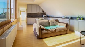 A modern kitchen with a built-in microwave, a dining area with a table and chairs, and a cozy seating area with a sofa and a blanket. - Apartment in Watou Near French Border (Poperinge)