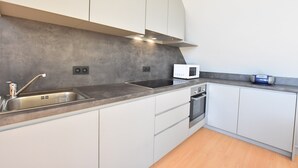 A modern kitchen with a stainless steel sink, a microwave, and a built-in oven. - Apartment in Watou Near French Border (Poperinge)
