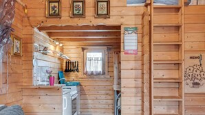 A cozy wooden cabin interior with a kitchen area, a dining table, and a staircase leading to a loft. - Charming Holiday Home With Private Garden (Niederaula)