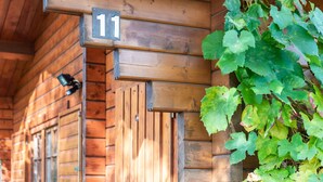 A wooden cabin with a number '11' sign, a window with shutters, and a vine growing outside. - Charming Holiday Home With Private Garden (Niederaula)