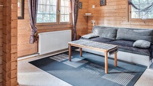 A cozy cabin interior with a wooden interior, a sofa, a table, and a window with curtains. - Charming Holiday Home With Private Garden (Niederaula)