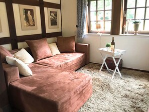 A cozy living room with a brown sofa, a small white table, and framed pictures on the wall. - Ferienhaus in Kirchdorf mit Reiterhof (Kirchdorf)