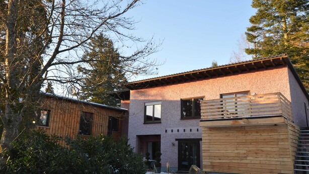 A modern two-story house with a wooden deck and a stone facade. - Wunderschone Ferienwohnung im Burgenland (Manderscheid)