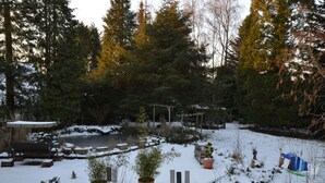 A snow-covered garden with a wooden bench, a pergola, and potted plants. - Wunderschone Ferienwohnung im Burgenland (Manderscheid)