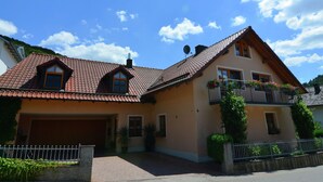 A two-story house with a red-tiled roof, a balcony with flower boxes, and a garage. - Apartment With Private Terrace in Prunn (Riedenburg)