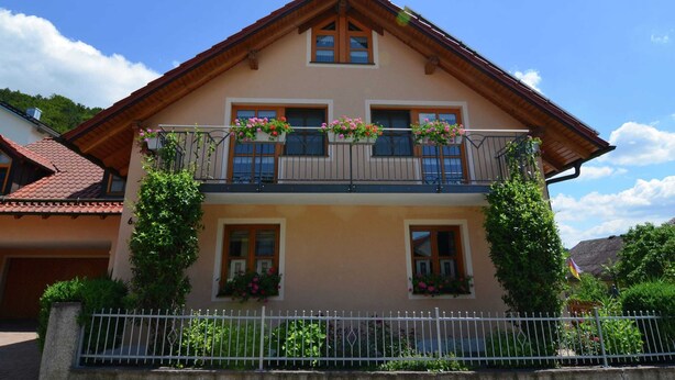 A two-story building with a balcony on the upper floor, featuring flower boxes and a wooden roof. - Apartment With Private Terrace in Prunn (Riedenburg)