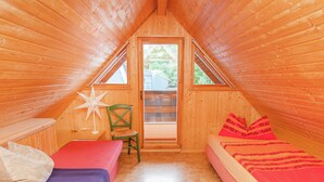 Une petite chambre mansardée en bois, avec deux lits, une chaise et une décoration en forme d’étoile.