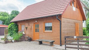 Une cabane en bois avec un toit recouvert de tuiles rouges, une porte en bois et une fenêtre.