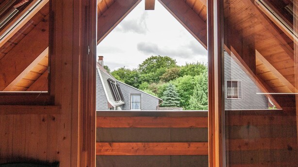 Un intérieur en bois donnant sur une maison, vue à travers une fenêtre.