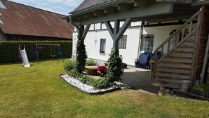 A covered outdoor area with a wooden staircase, a small garden with plants and a bench, and a swing set. - Flat Near the ski Area in Medebach (Medebach)