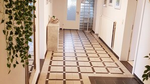 A hallway with a checkered floor pattern, a door with frosted glass, and a radiator on the wall. - Flat Near the ski Area in Medebach (Medebach)