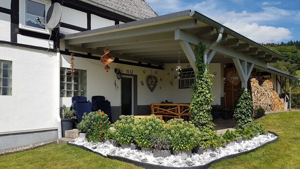 A traditional building with a covered porch, outdoor seating, and a stone wall garden. - Flat Near the ski Area in Medebach (Medebach)