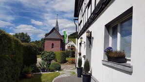 A pathway leading to a building with a brick structure and a white facade. There are potted plants and a small brick building in the background. - Flat Near the ski Area in Medebach (Medebach)