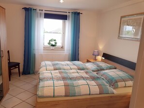 A bedroom with a bed, a chair, a window with curtains, a bedside lamp, and a framed picture on the wall. - Flat Near the ski Area in Medebach (Medebach)