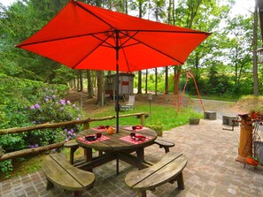 A picnic table with a red umbrella, surrounded by greenery and a swing set. - Chalet in a Green and Peaceful Environment (Houffalize)
