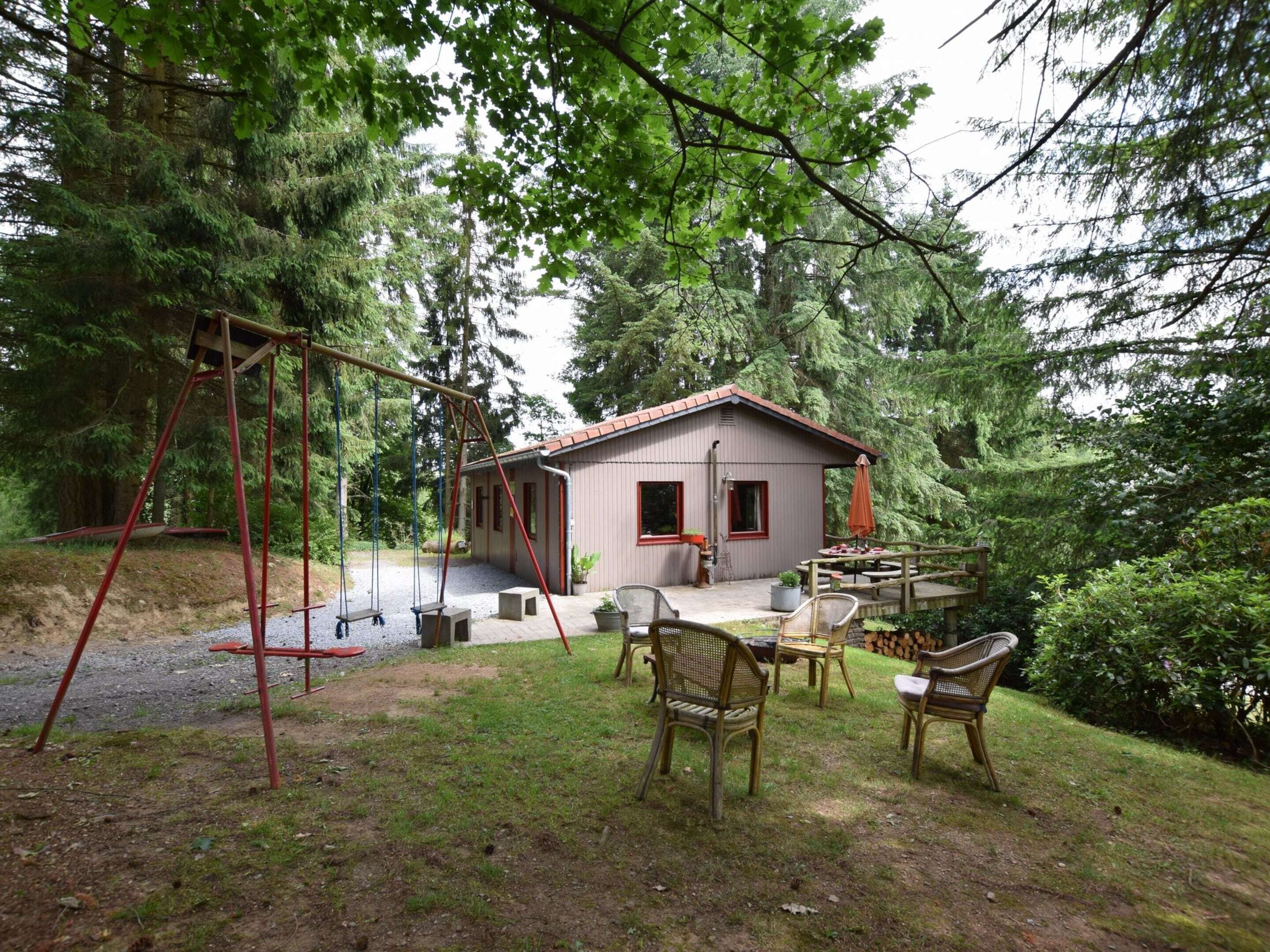 A rustic cabin with a swing set, outdoor seating, and a garden area.