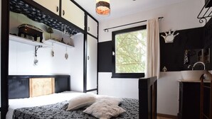 A bedroom with a bed, a window with a view, a sink, and a cabinet. - Chalet in a Green and Peaceful Environment (Houffalize)