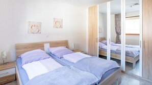 A bedroom with two beds, a wooden headboard, a nightstand, a mirror, and two wall-mounted pictures. - Wohnung in der Nahe des Skigebietes Battenberg (Battenberg)