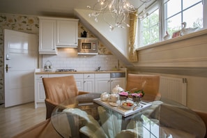 A kitchen with white cabinets, a microwave, and a dining area with a glass table and chairs.