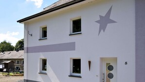 Un edificio moderno con facciata bianca, un elemento decorativo a forma di stella e una porta contrassegnata dal numero 5.