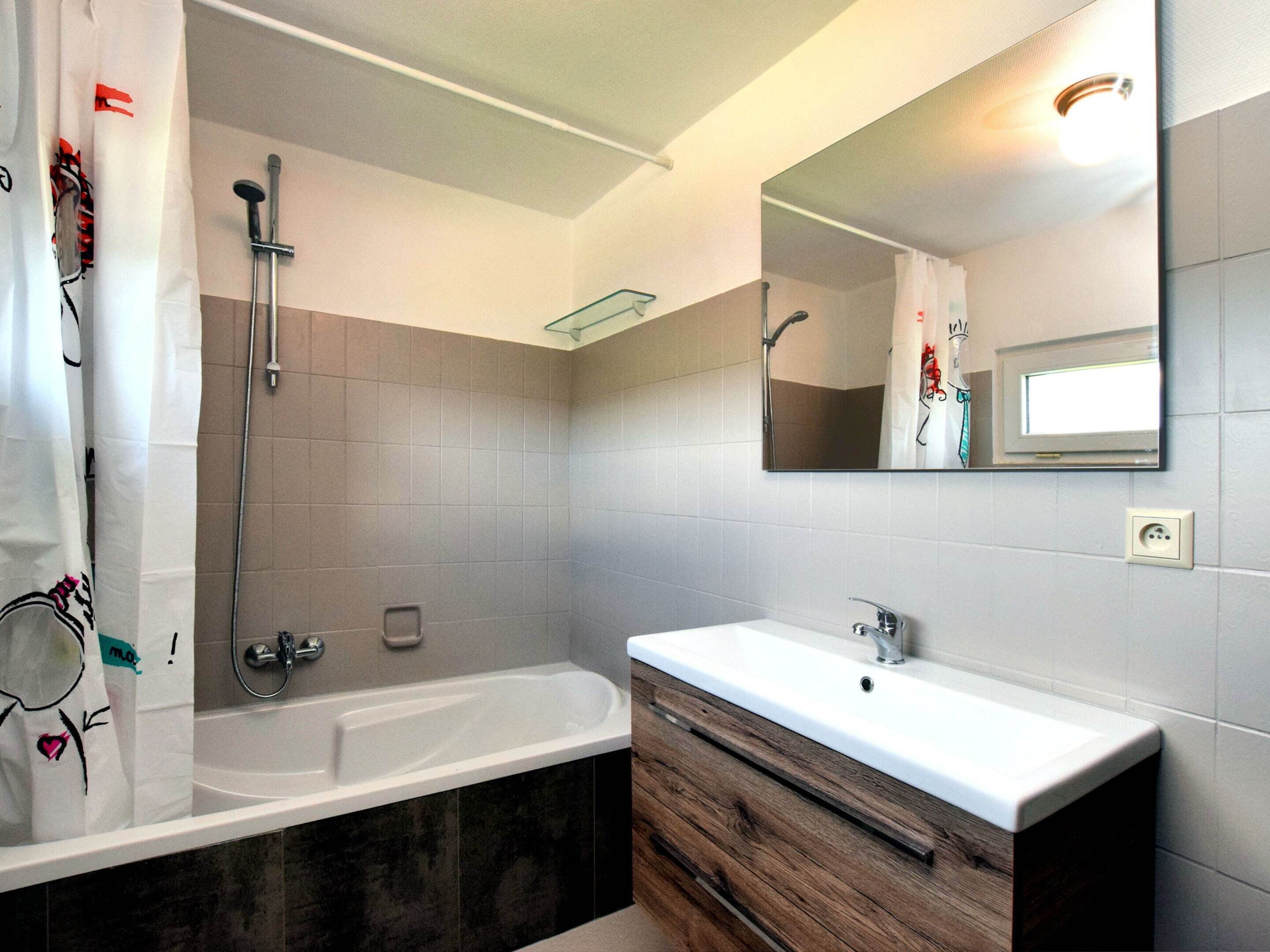 A modern bathroom with a bathtub, a vanity with a mirror, and a shower area.