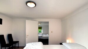 Una camera da letto con un letto, una sedia e una porta che dà su un'altra stanza.