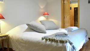 A neatly made bed with a quilted duvet, pillows, and a decorative pom-pom fringe.