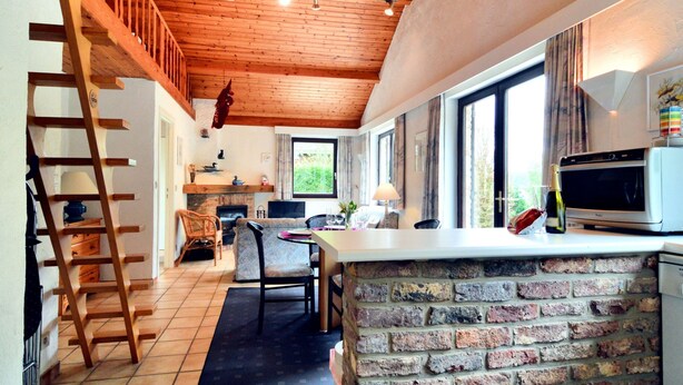 Een rustieke keuken met een keukeneiland van baksteen, een houten plafond en een open haard.