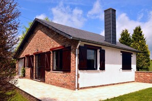 Une maison à deux étages avec une façade en briques, une cheminée et un patio carrelé.