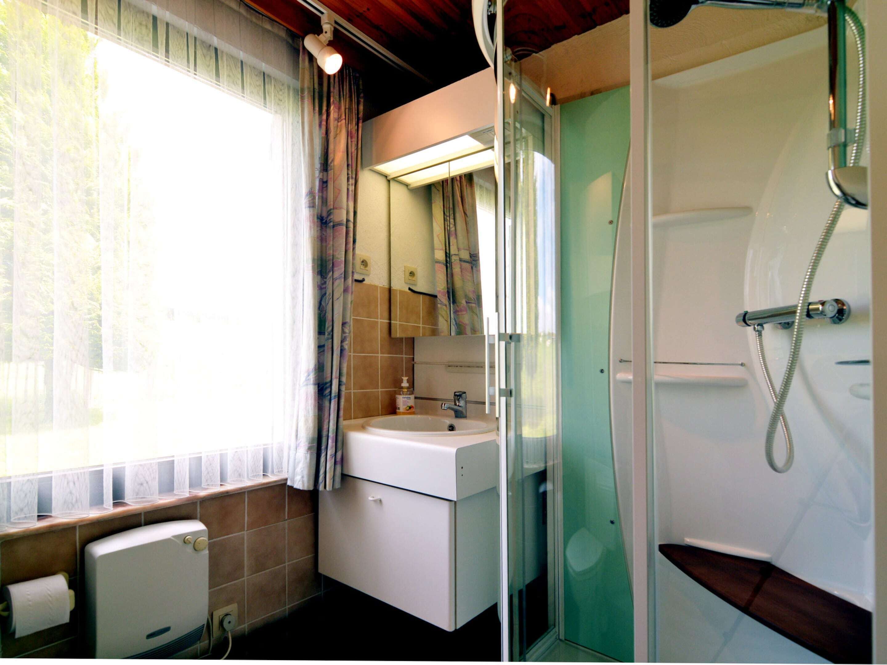 Un baño con lavamanos, espejo, ducha e inodoro.