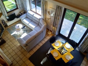 Un salon avec un canapé, une table à manger dressée pour quatre personnes et un téléviseur.