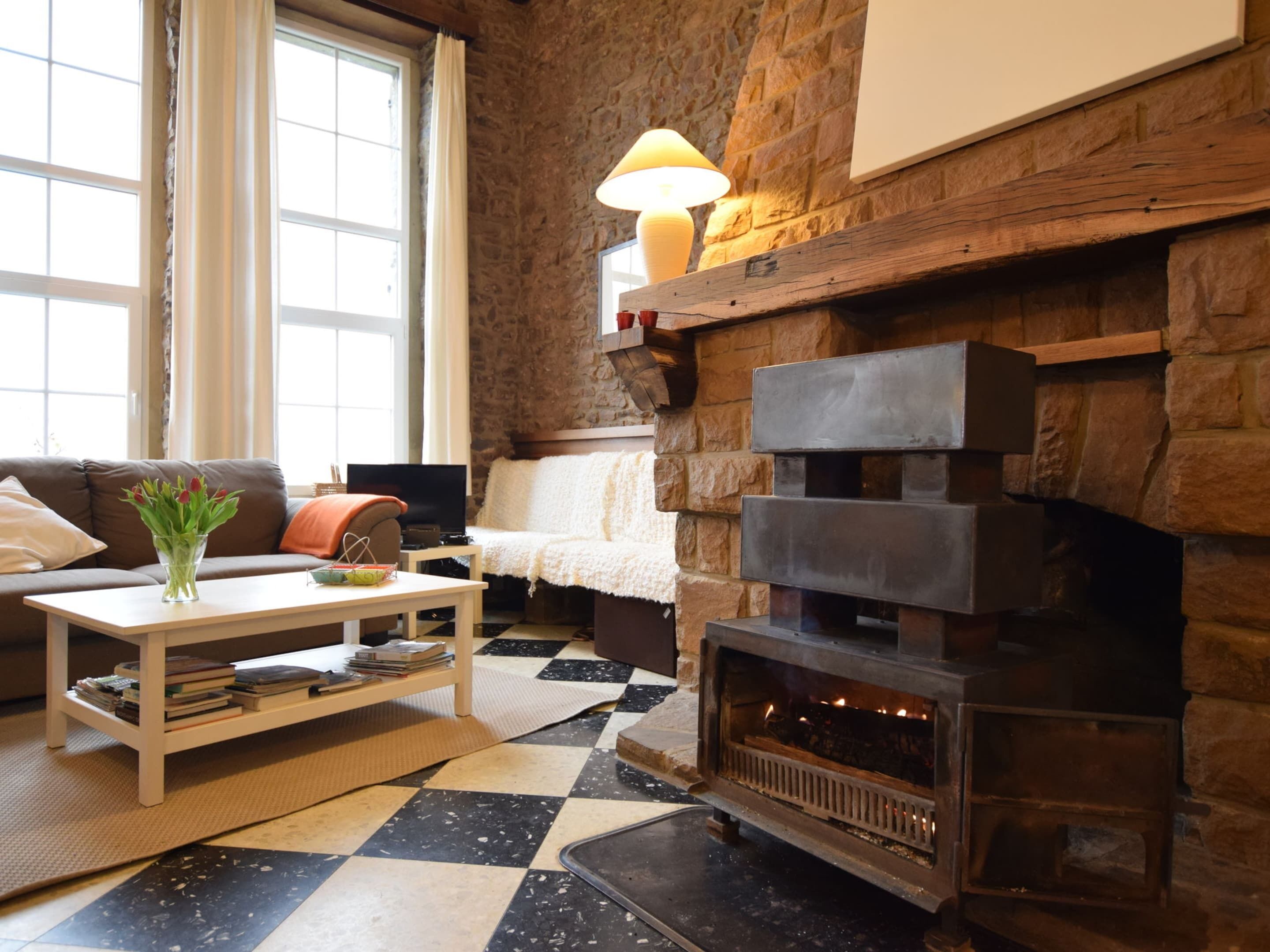 Un salon chaleureux avec une cheminée en pierre, un canapé, une table basse et un téléviseur.