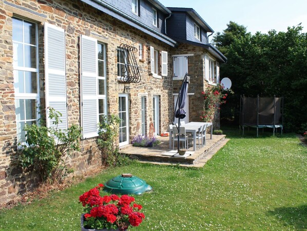 A stone house with white shutters, a patio with a table and chairs, and a green umbrella. - Charming House, Perfect for Family Holidays (Erezee)