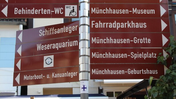 A directional signpost with multiple arrows pointing to various destinations such as Klosterkirche, Tourist-Information, and Munchhausen-Museum. - Apartment in Bodenwerder mit Balkon (Bodenwerder)