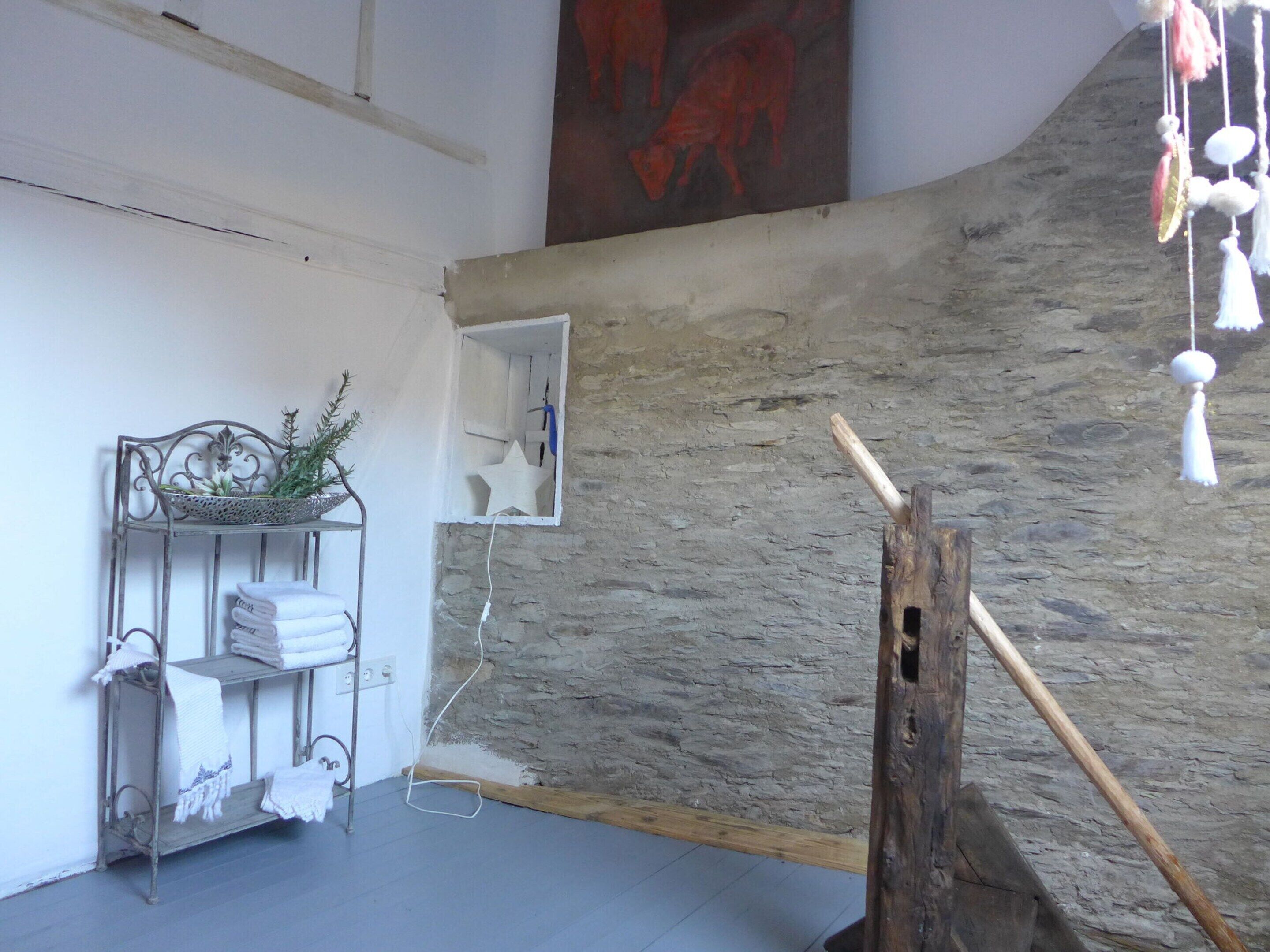 A room with a stone wall, a metal shelf with towels, and a wooden post.