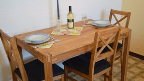 A wooden dining table with four chairs, a bottle of wine, and a glass of water. - Apartment Welschbilling Near Trails (Welschbillig)