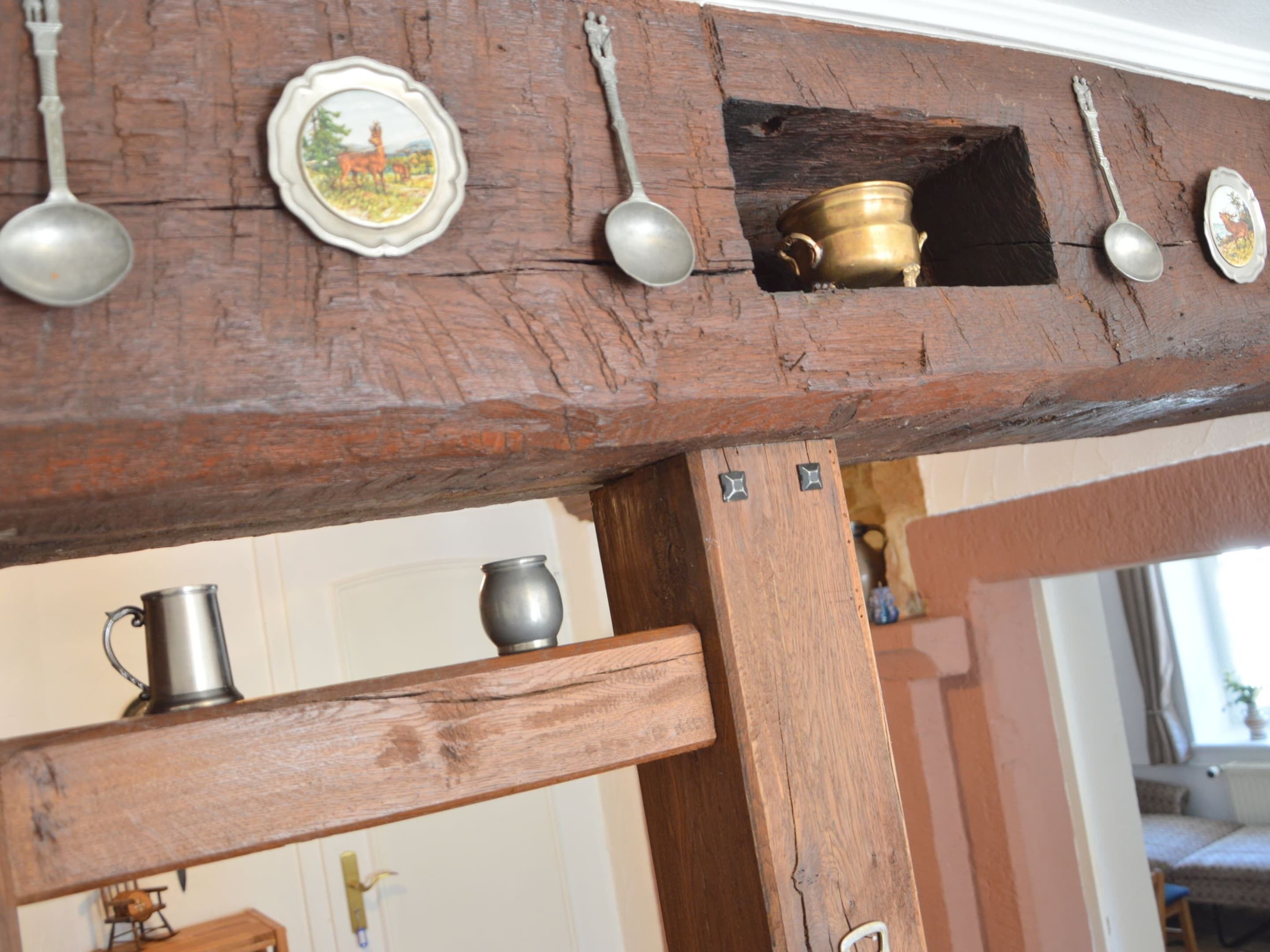 Een rustieke houten balk met metalen keukengerei en een decoratief bord.
