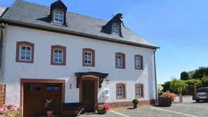 A large, white building with a dark roof, multiple windows, and a central entrance. - Apartment Welschbilling Near Trails (Welschbillig)