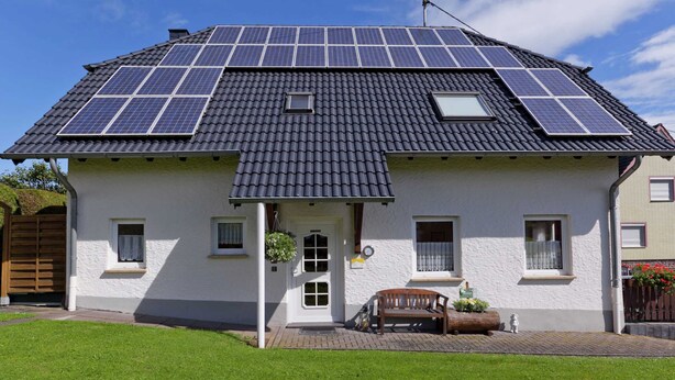 A house with a sloped roof covered in solar panels, a white exterior, and a small front porch with a bench. - Modern Apartment in Bolsdorf With Sauna (Hillesheim)