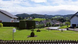 A residential area with houses, a well-maintained lawn, and a view of distant hills. - Modern Apartment in Bolsdorf With Sauna (Hillesheim)