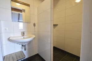 Casa de banho com lavatório branco, espelho e porta-toalhas.
