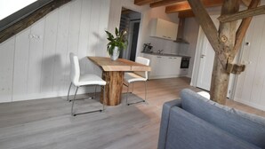 A modern kitchen with white cabinets and a wooden ceiling beam. - Apartment Near Groote Keeten Beach (Callantsoog)