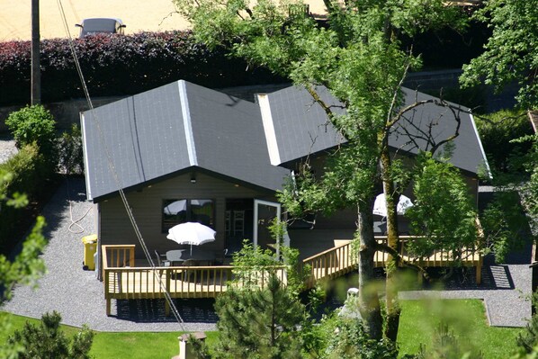 A house with a sloped roof, a wooden deck, and a small outdoor seating area with a table and chairs.