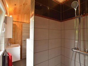 A modern bathroom with a wooden ceiling, a white sink, and a glass shower enclosure.