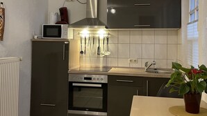 A compact kitchen with a built-in oven, microwave, and stainless steel range hood. - Apartment Near the Forest in Meisburg (Meisburg)
