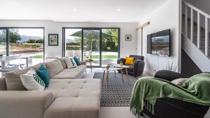A modern living room with a sofa, a coffee table, and a TV. - Holiday Home Beaufort With Private Pool (Beaufort)